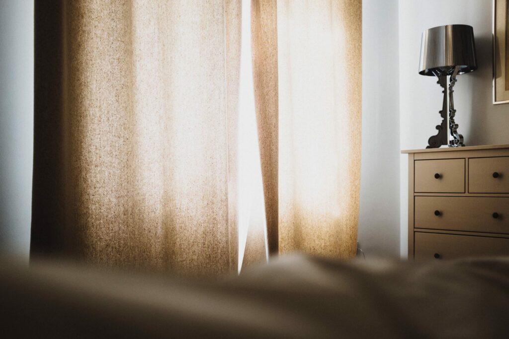 A curtain dimming a bedroom by blocking light from the outside.